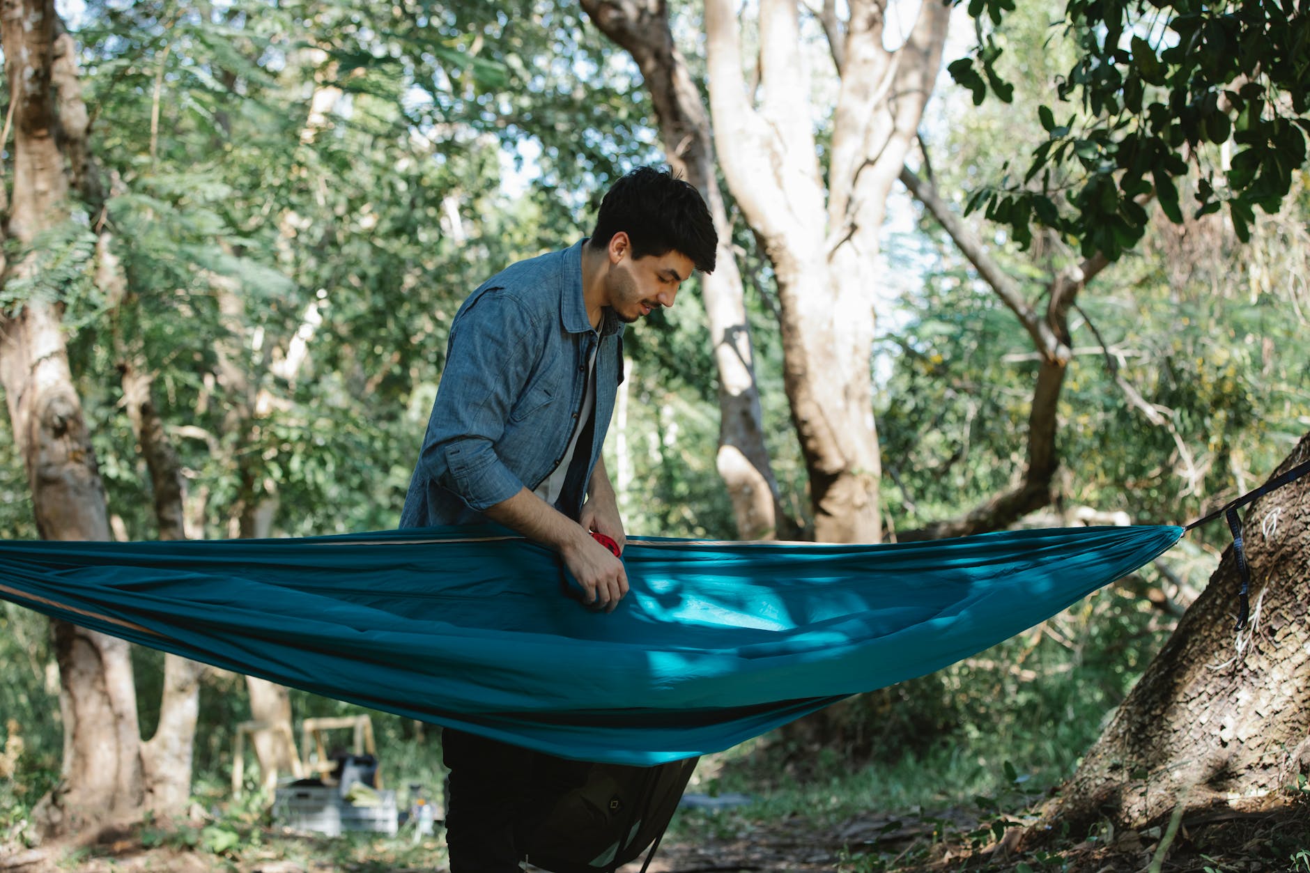 a young man enjoys a tranquil moment in a hammock surrounded by a lush green forest setting