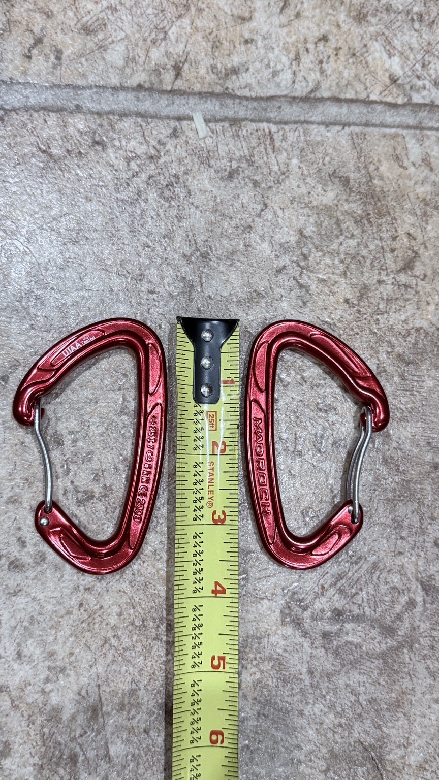 Two red Mad Rock wiregate carabiners from Mike’s setup beside a tape measure.
