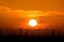 Wind turbines silhouetted against a stunning sunset, showcasing renewable energy in nature