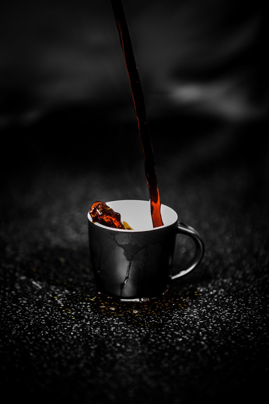 liquide brun coulant sur une tasse en ceramique noir et blanc photographie couleur selective