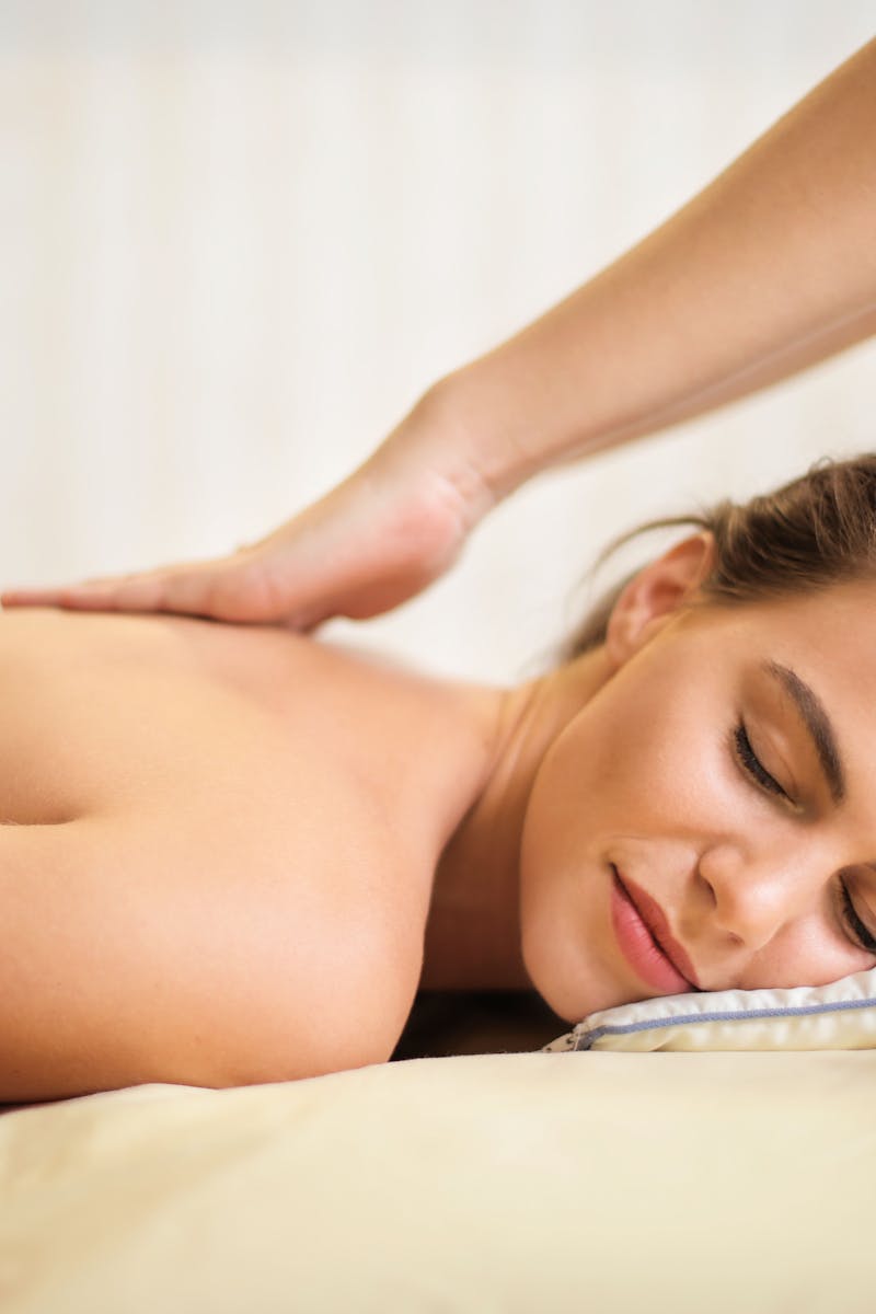 femme aux seins nus allongee sur le lit se faire masser