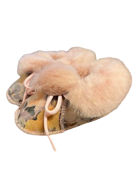 Chaussons bébé en peau de mouton à fleurs sur fond jaune, col en laine rose poudré et lacets roses