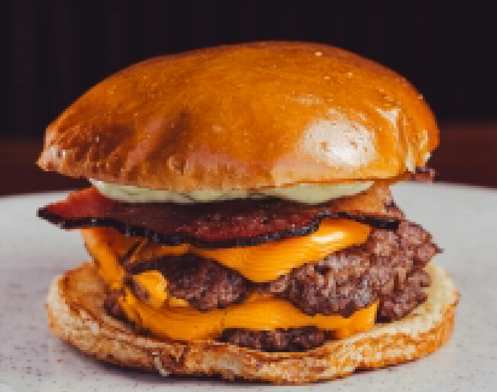 Gros plan d'un cheeseburger juteux avec du bacon, du fromage et de la sauce sur un pain