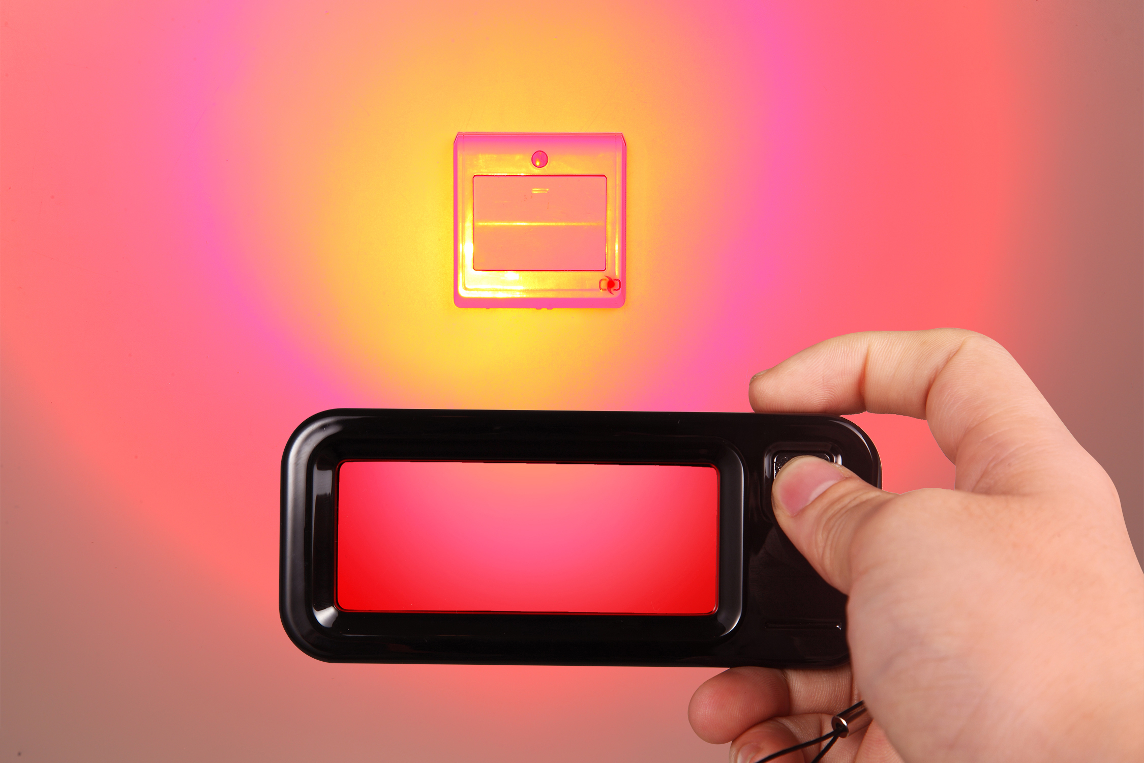 Handheld optical detector in front of a device, illustrating hidden camera detection