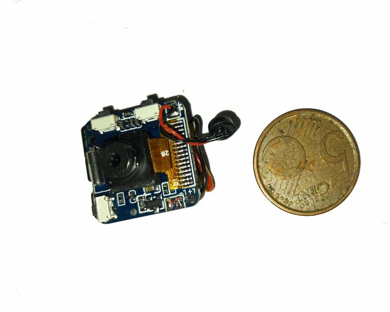 Mini spy camera circuit board beside a coin for size comparison