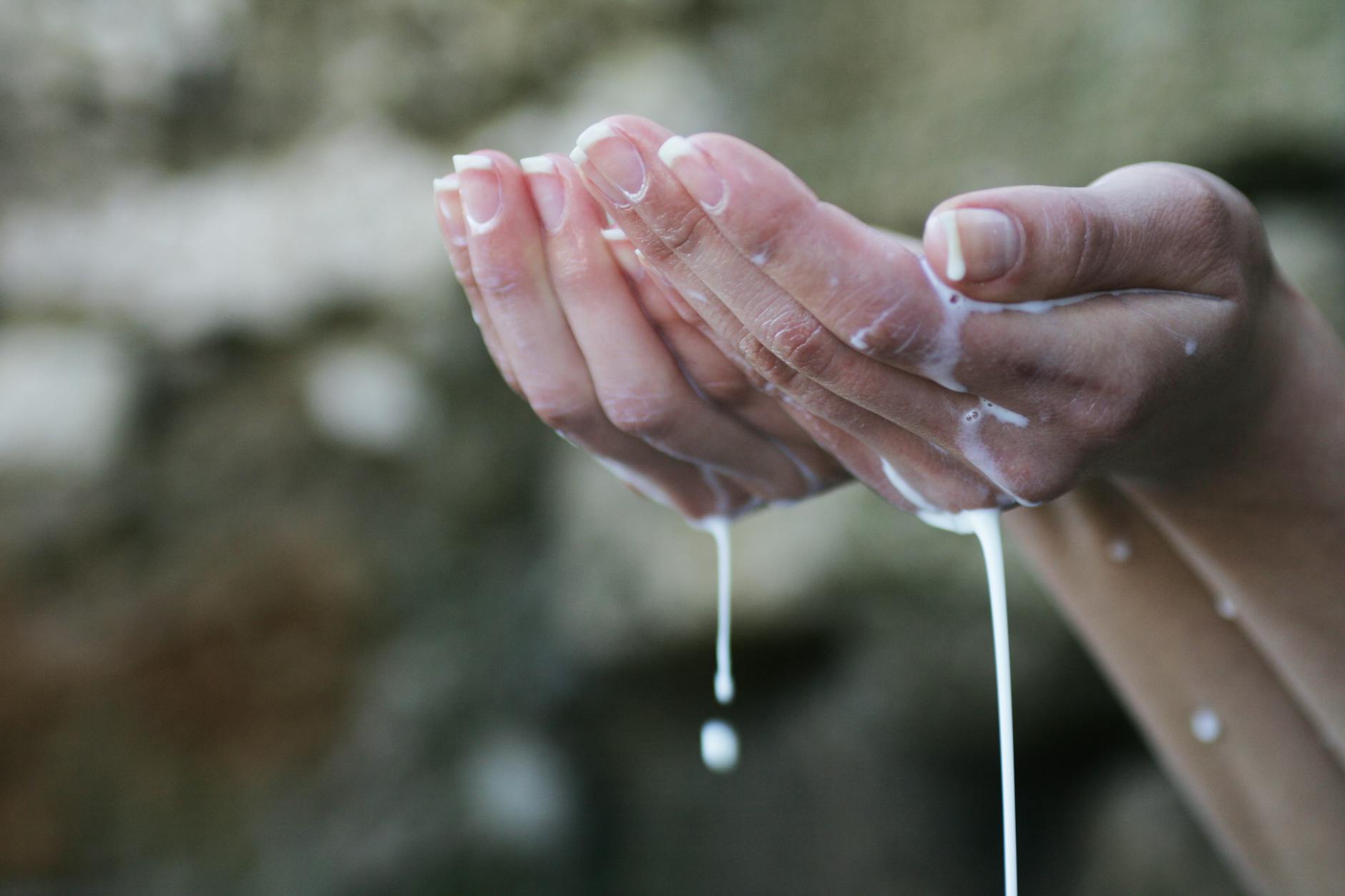 les mains de la personne couvertes de liquide blanc