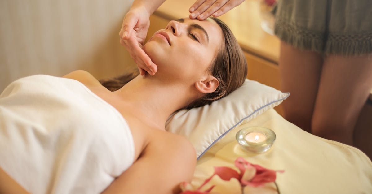 femme enveloppee dans une serviette blanche allongee sur le lit se faire masser