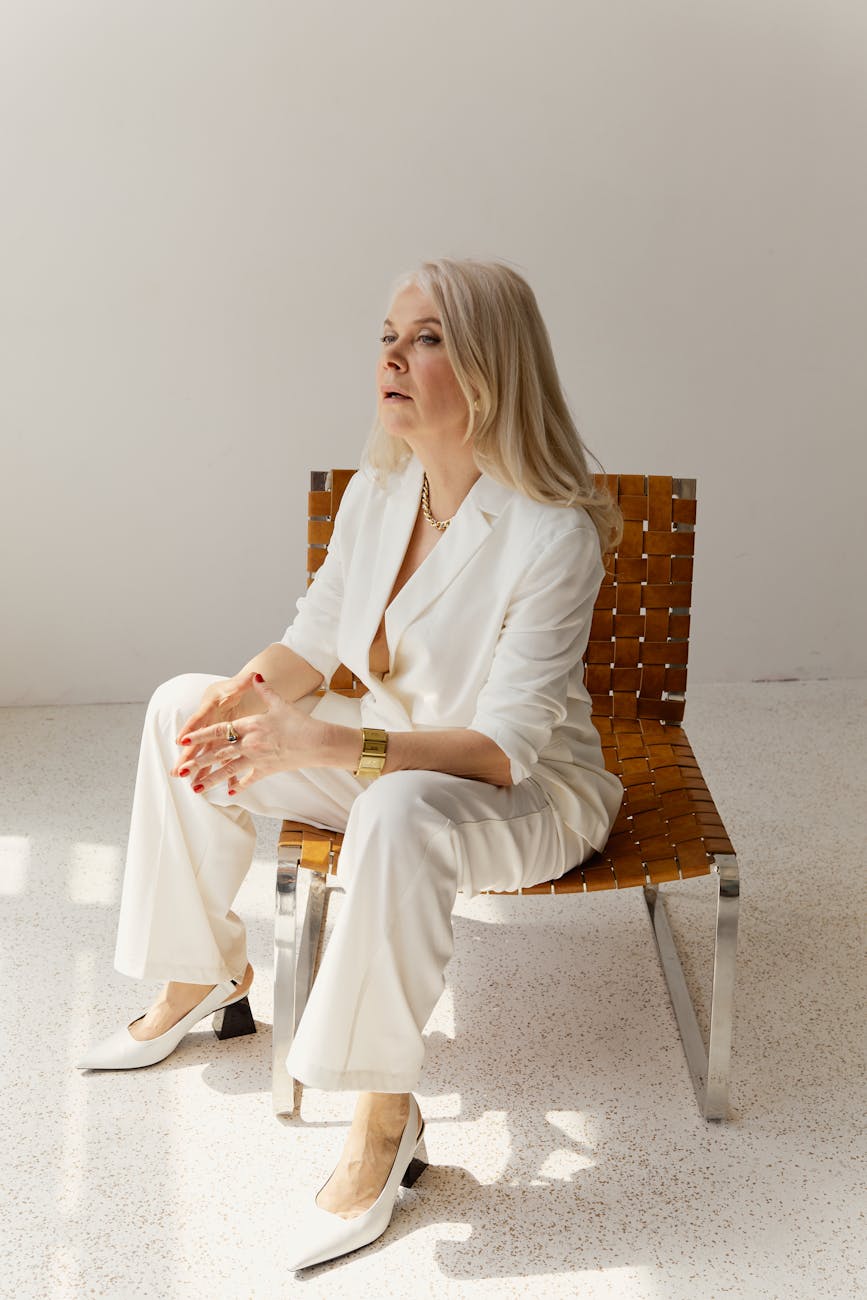 femme en blazer blanc assise sur une chaise marron