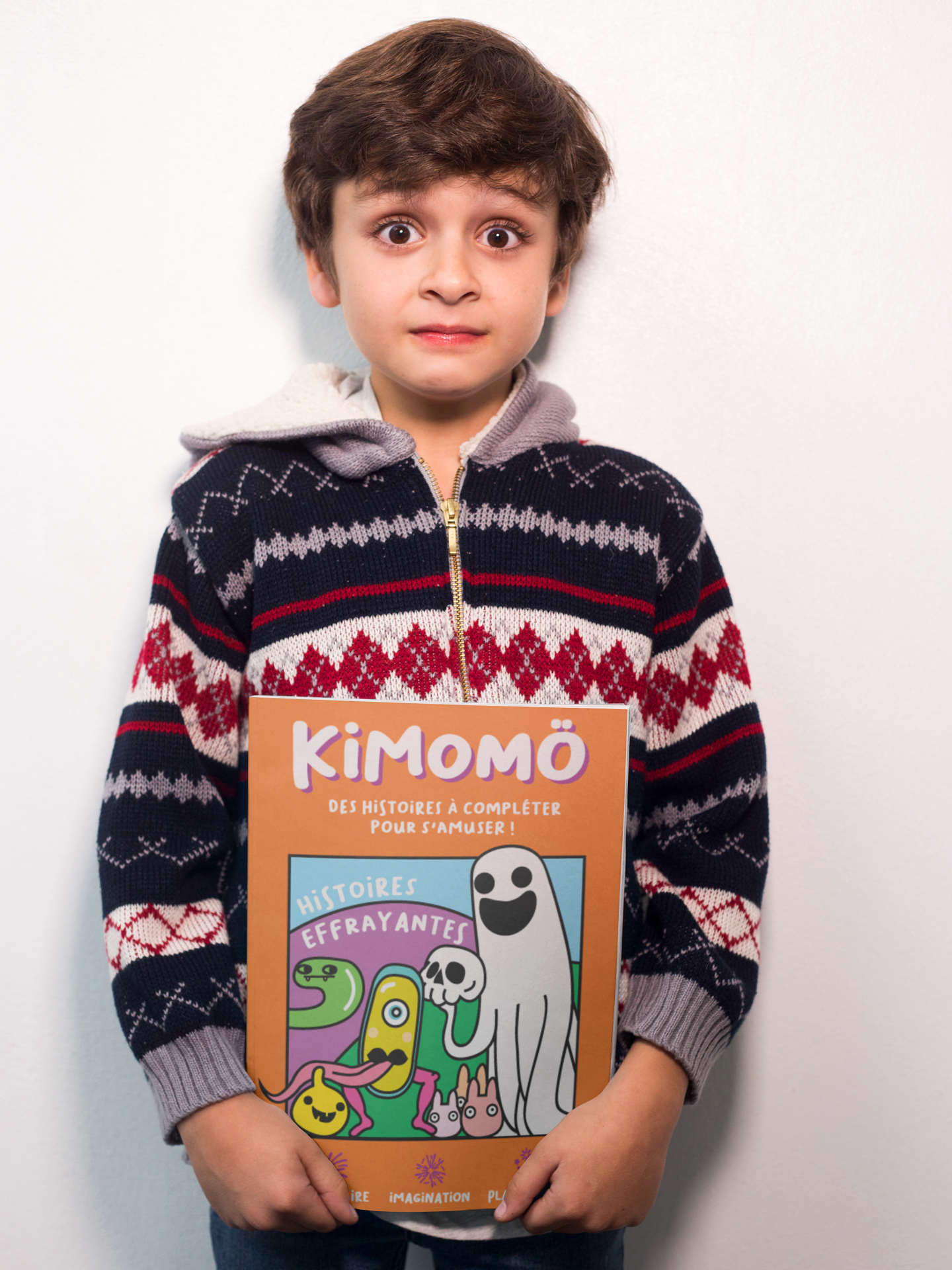 surprised-boy-holding-a-book-mockup-against-a-white-wall-a19219