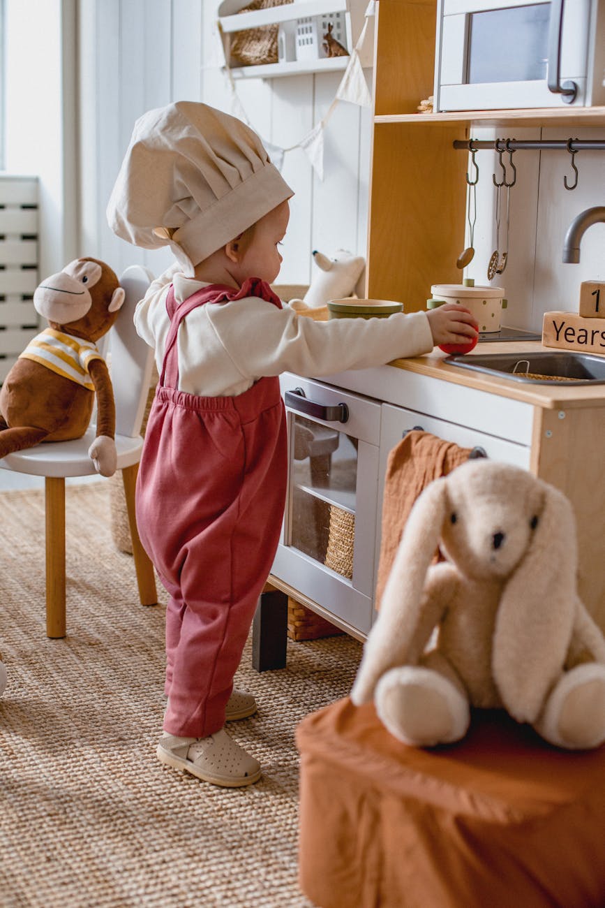 bebe portant un chapeau de chef jouant avec une cuisine jouet portant un chapeau de chef