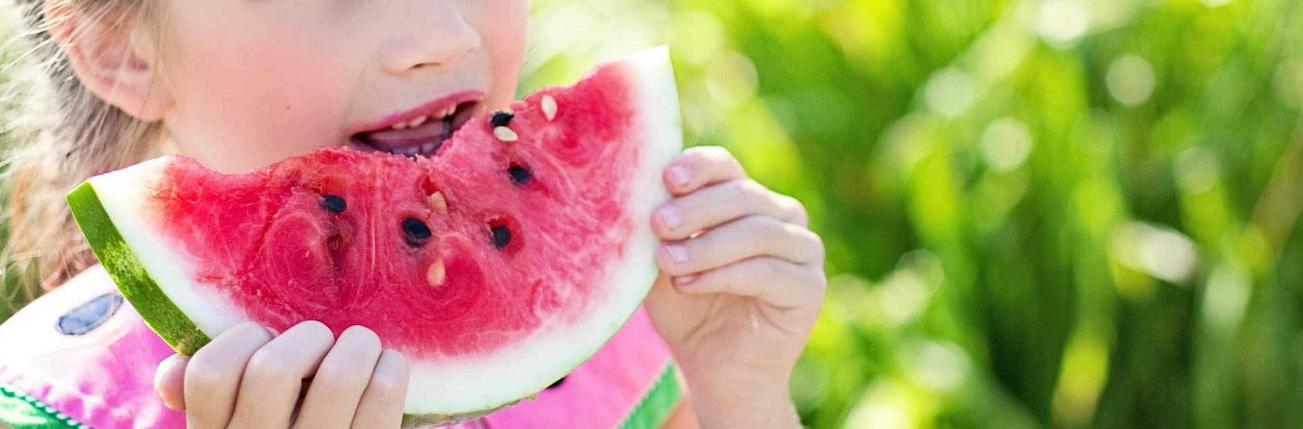 fille de manger des fruits de pasteque en tranches a cote de la table