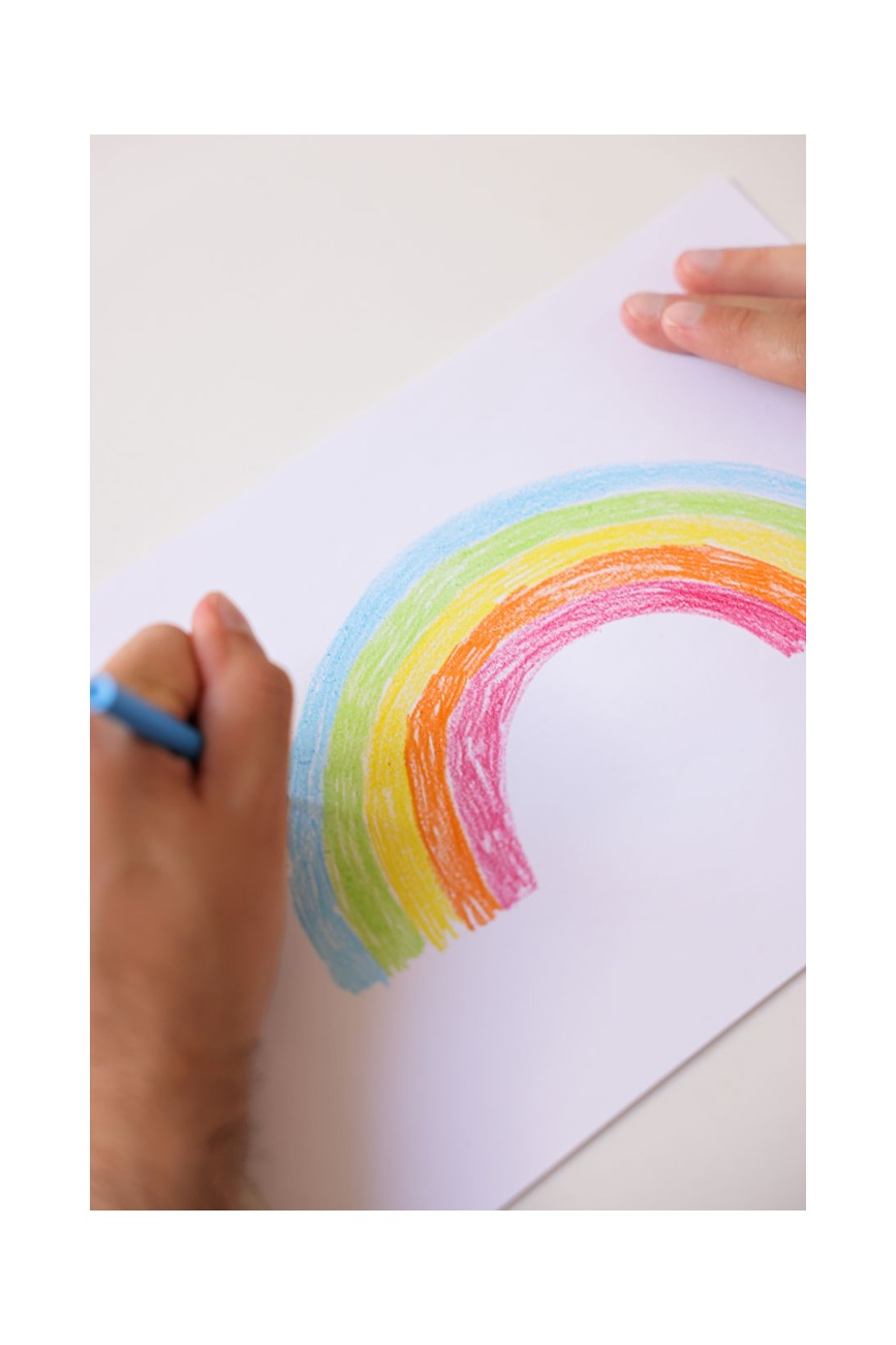 gros plan d une main dessinant un arc en ciel colore sur du papier blanc