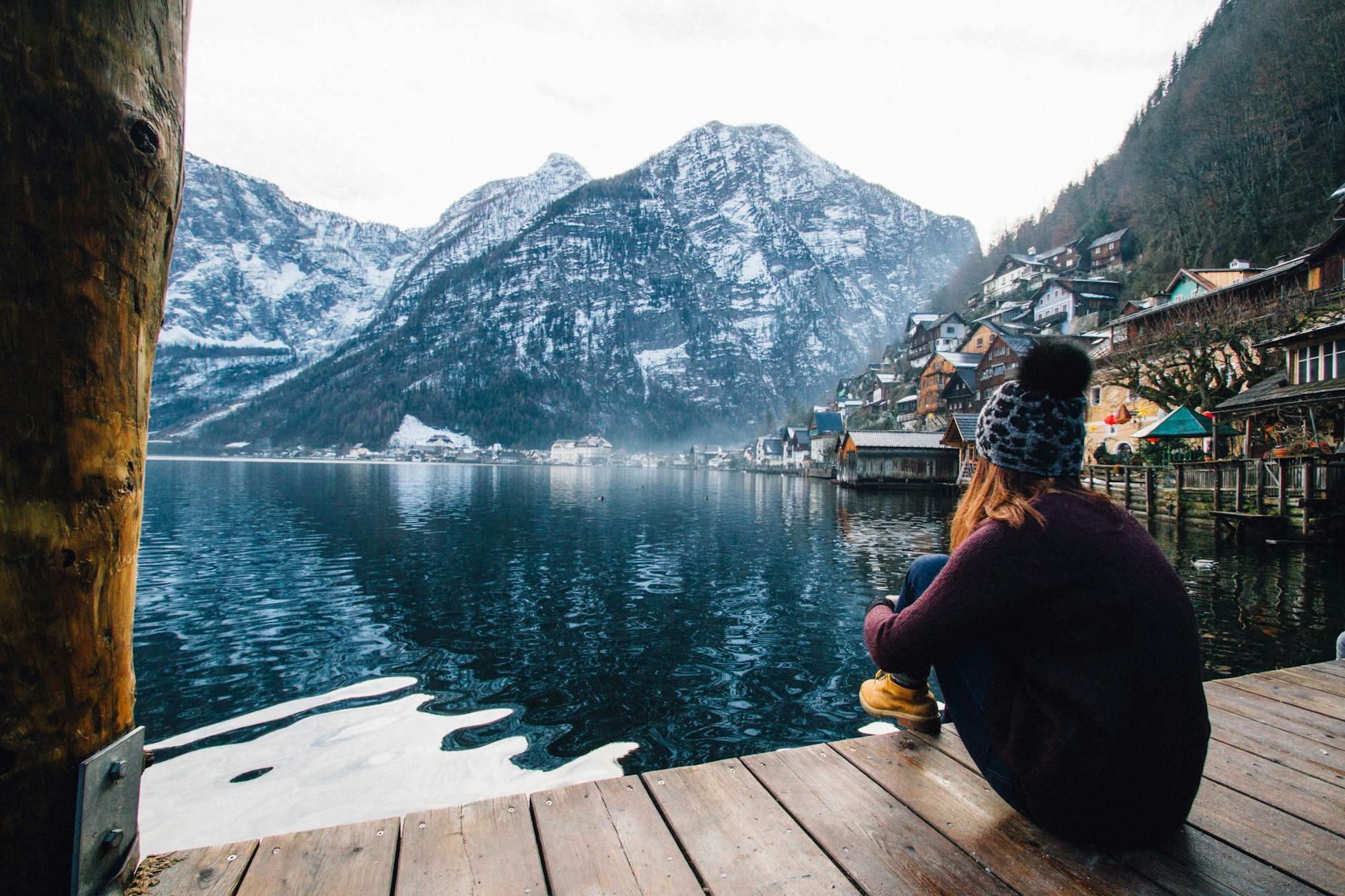 femme en pull violet assis sur un plancher en bois avec vue sur le lac et les montagnes
