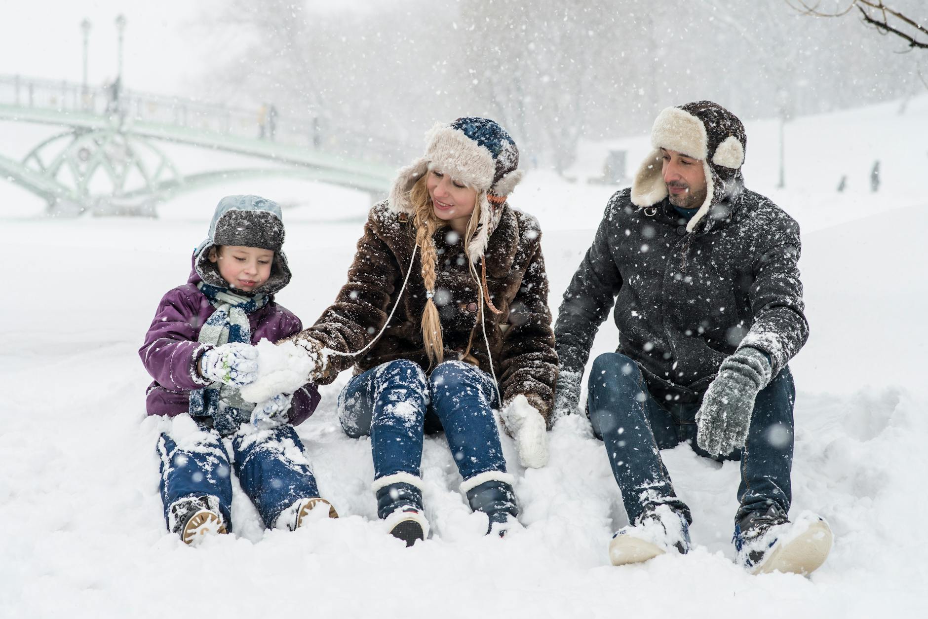 femme homme et fille assis sur la neige