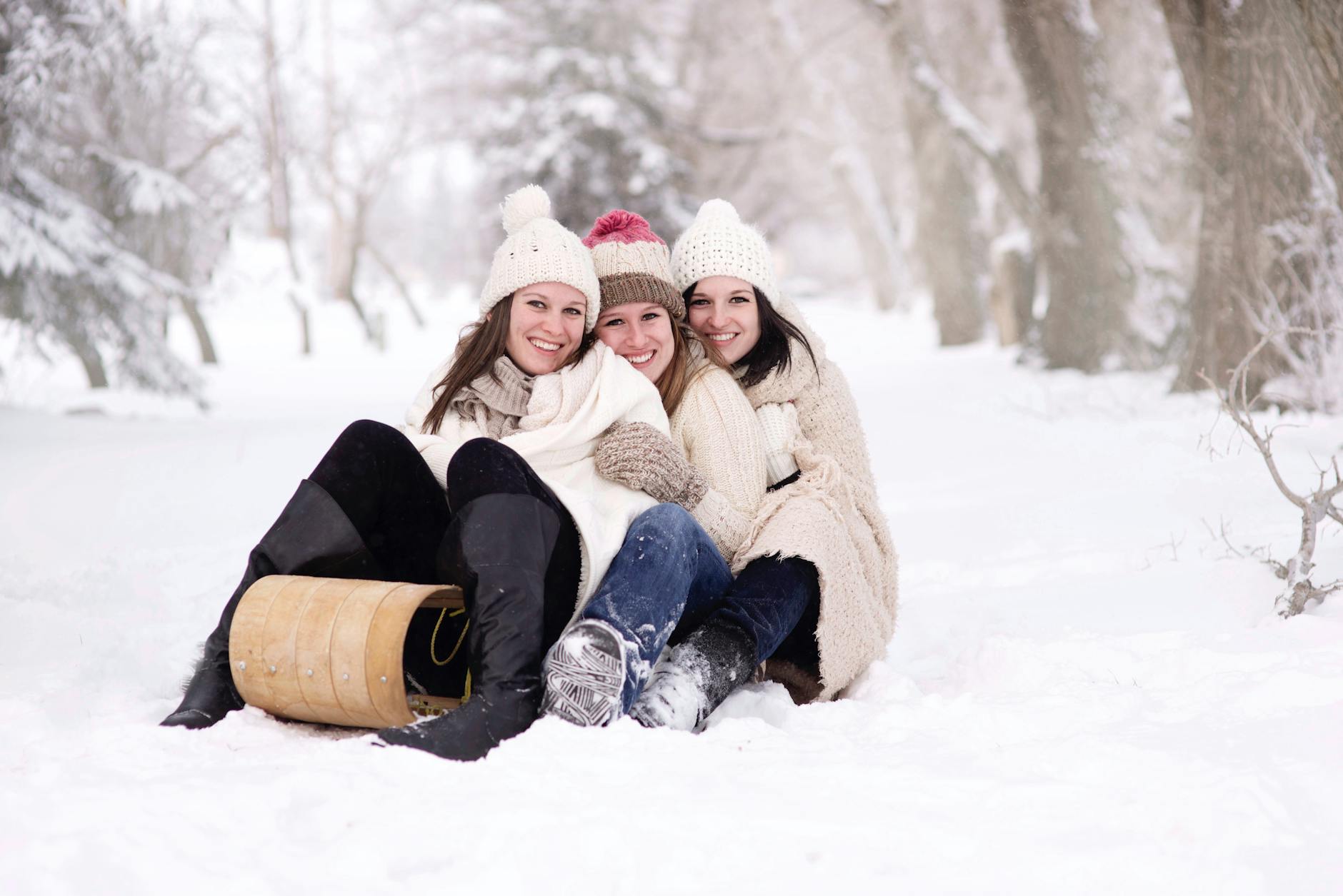 trois femmes assises sur un sol couvert de neige pendant la journee