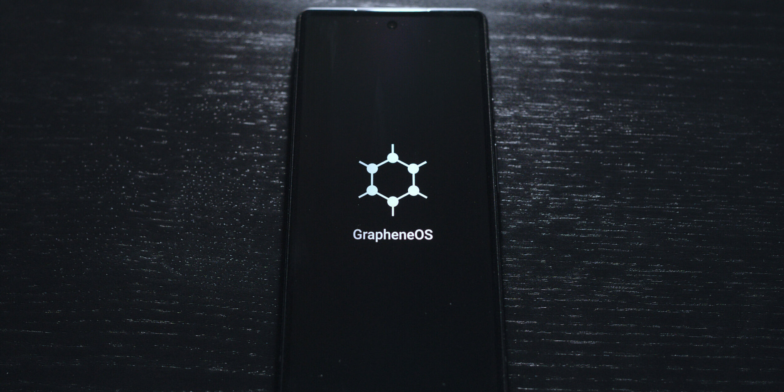 Schwarzes Smartphone mit GrapheneOS-Logo auf dem Bildschirm