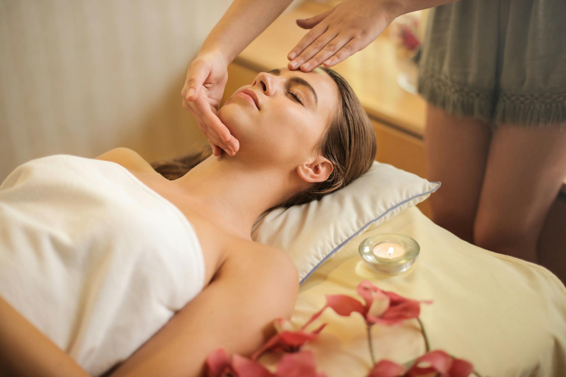 femme enveloppee dans une serviette blanche allongee sur le lit se faire masser