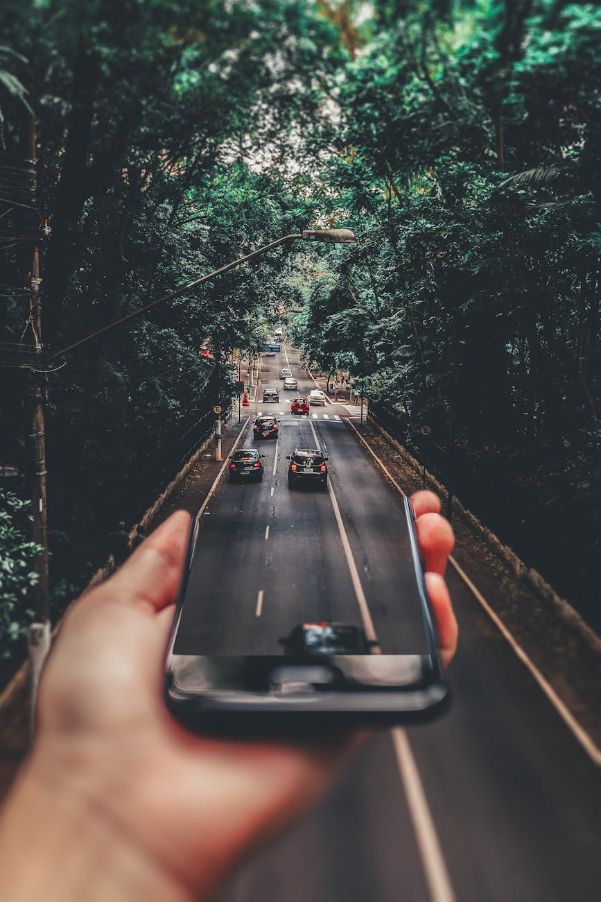 photographie en perspective forcee de voitures roulant sur la route sous le smartphone
