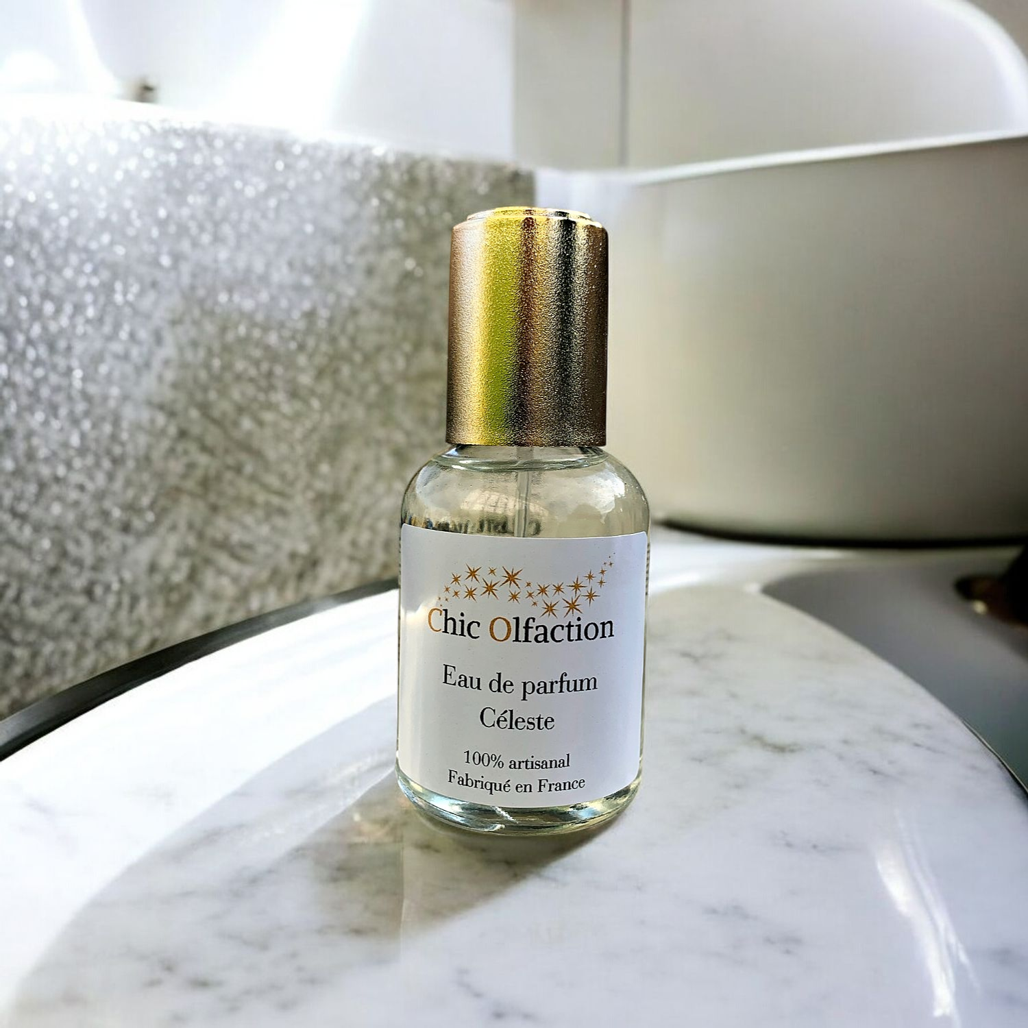 flacon deau de parfum de la marque chic olfaction portant le nom de céleste de la famille olfactive fleurie posé sur le plan de travail en marbre dune salle de bains