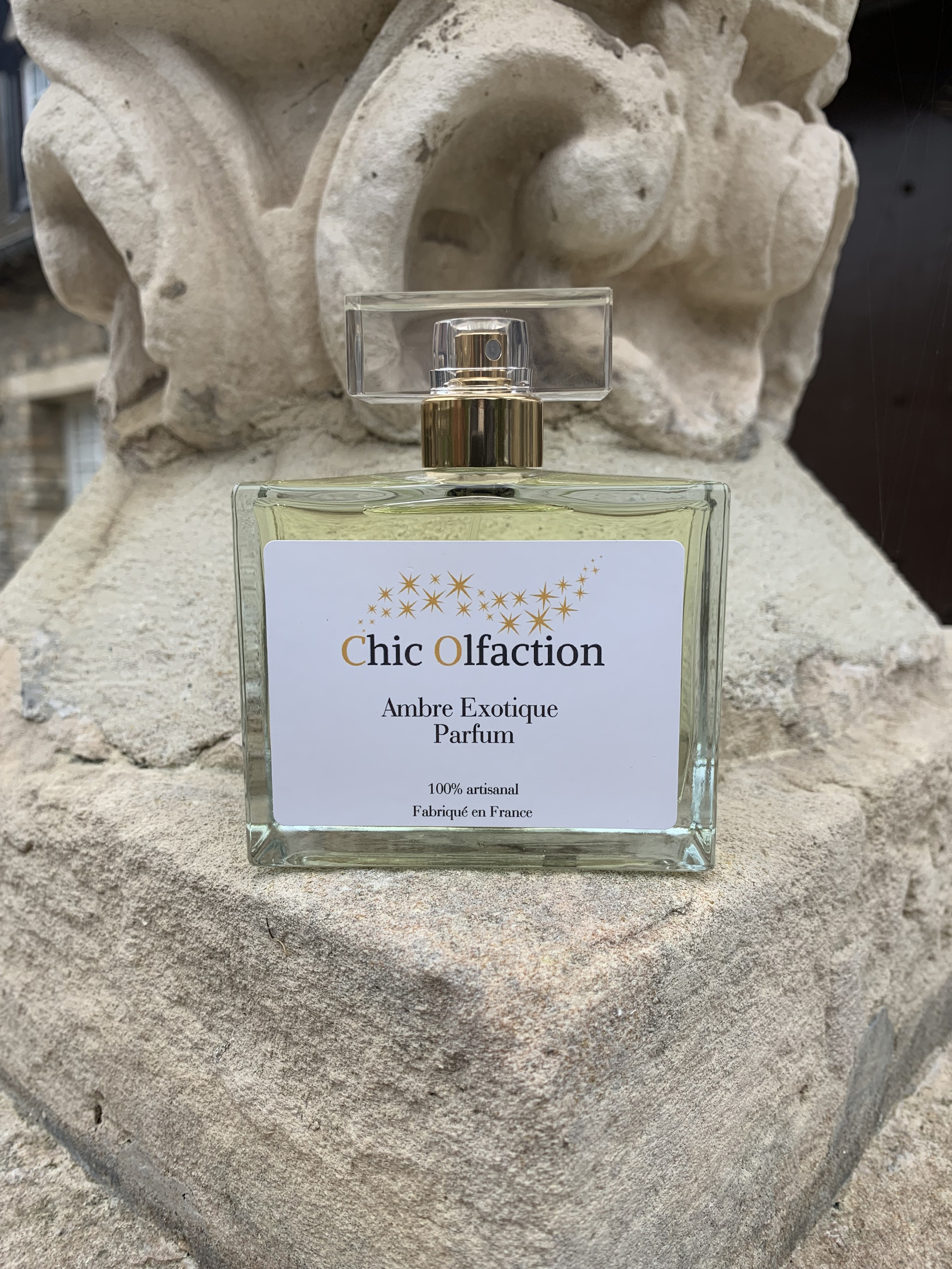 flacon 100 ml de parfum ambre exotique de la marque chic olfaction posée sur une pierre de Caen