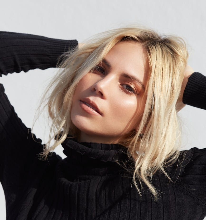 femme en pull a col roule noir avec des cheveux blonds