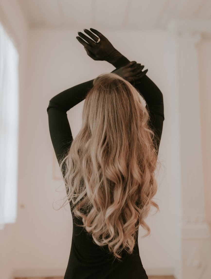 femme elegante aux longs cheveux blonds et aux gants noirs posant a l interieur photo de mode moderne et elegante