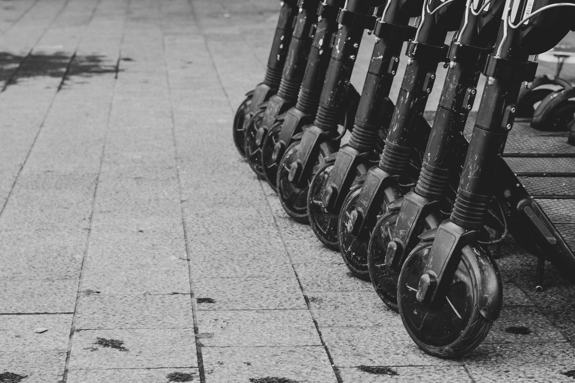 black and white photo of lined up electric scooters on pavement in brussels