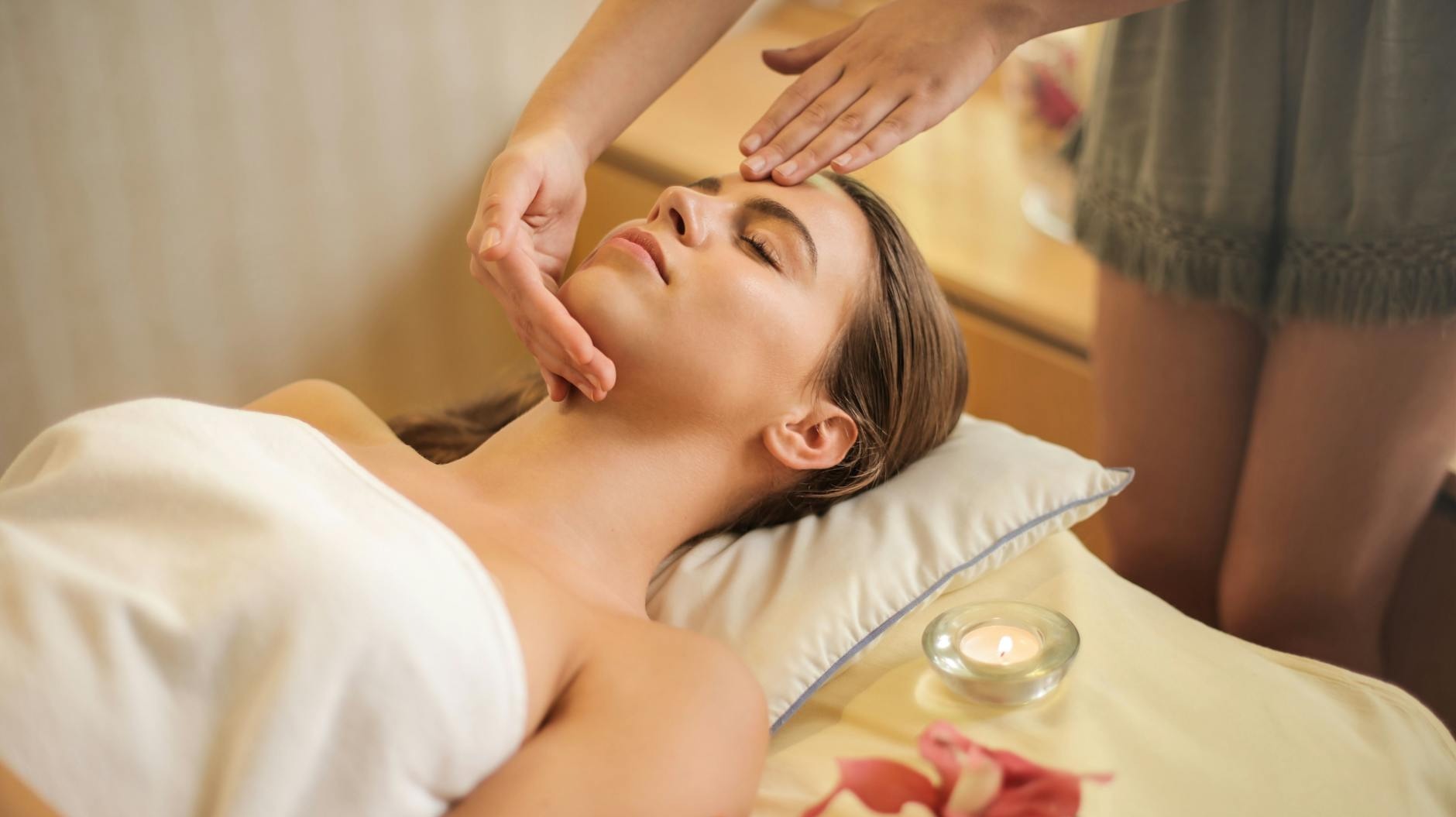 femme enveloppee dans une serviette blanche allongee sur le lit se faire masser