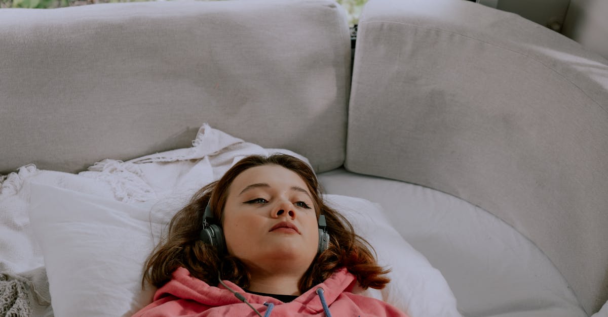 Fille En Veste Zippée Bleue Et Rouge Allongée Sur Un Lit Blanc