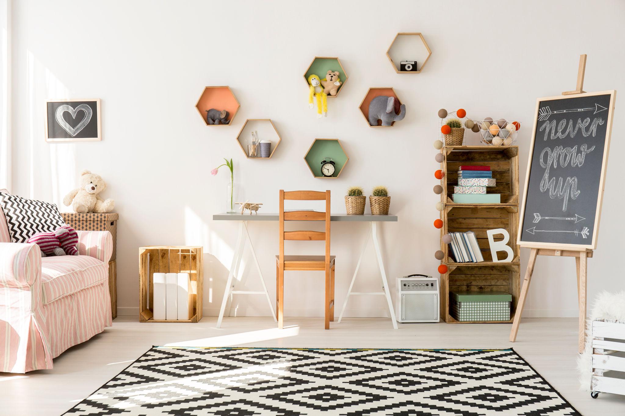 Petit bureau et rangements dans une chambre d’enfant avec jouets et tableau