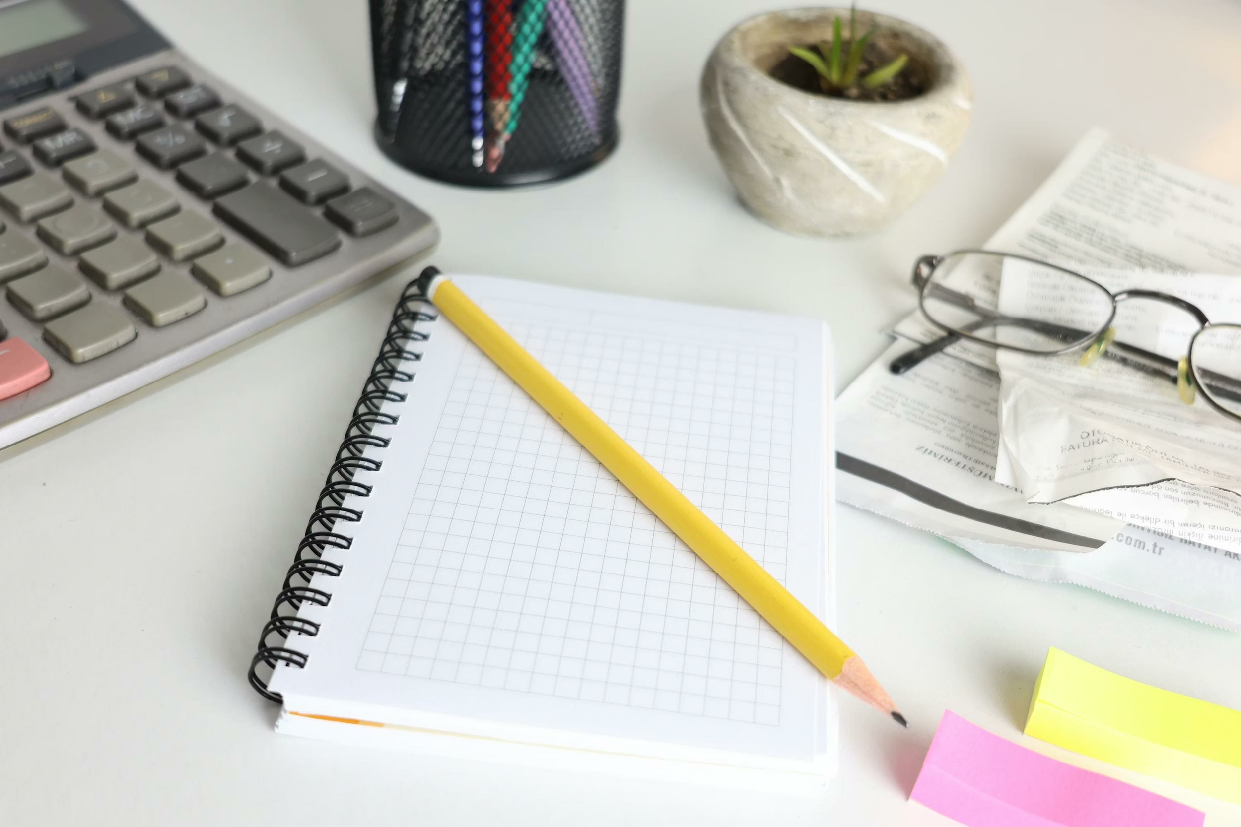 Carnet quadrillé, crayon et calculatrice pour organiser ses tâches