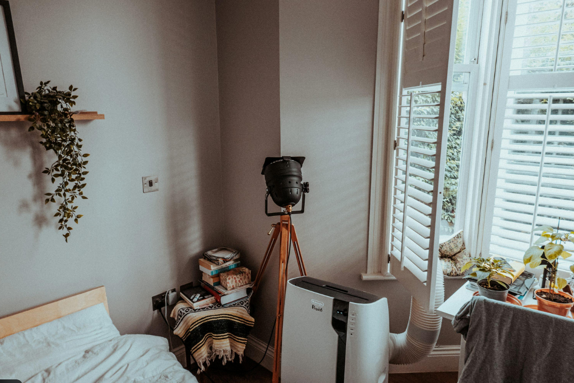 Climatiseur mobile installé près d’une fenêtre avec une gaine d’évacuation vers l’extérieur