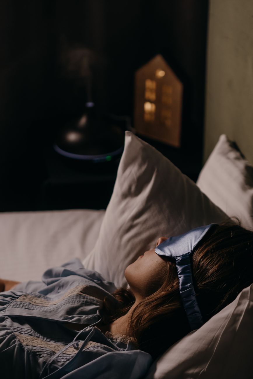 Une femme repose dans son lit avec un masque de sommeil sur les yeux