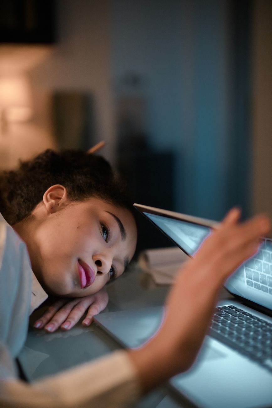 Une femme pose la tête sur son bureau devant un ordinateur portable