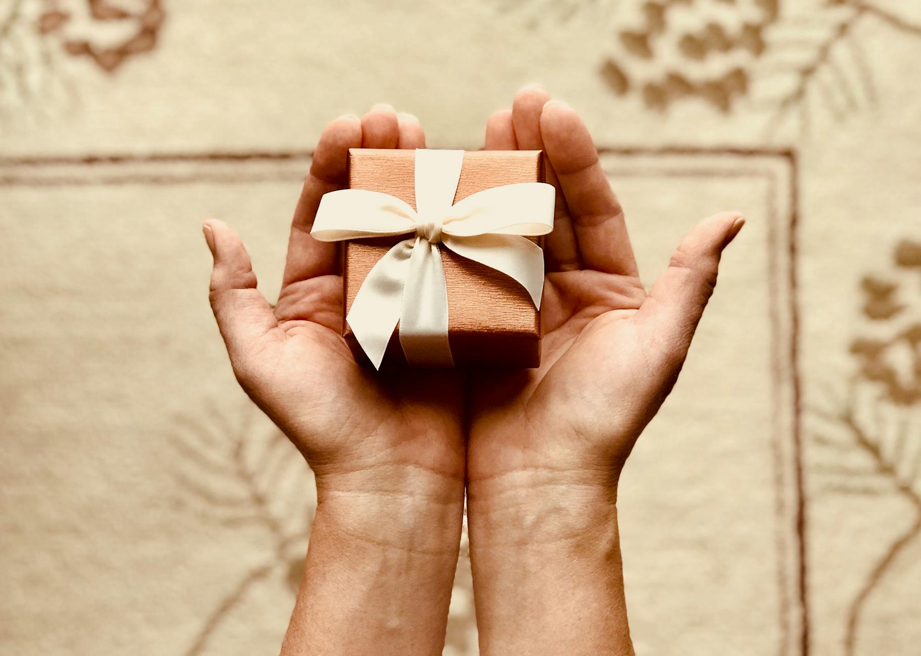 la personne tient une boite cadeau marron