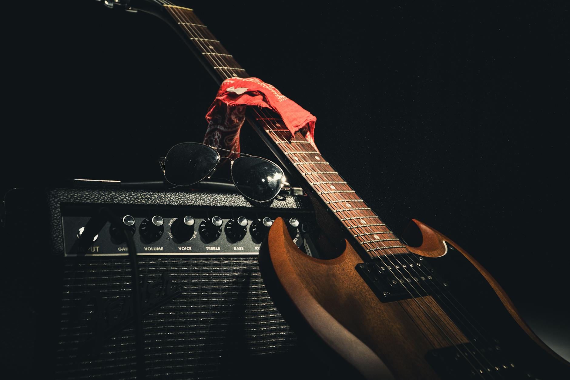 styled electric guitar resting on amplifier with sunglasses and scarf capturing rock vibe