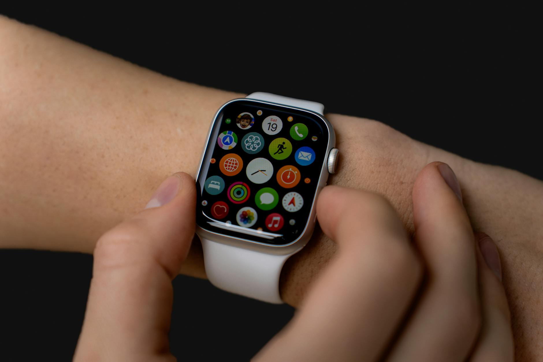 close up of person interacting with a smartwatch displaying apps on a dark background