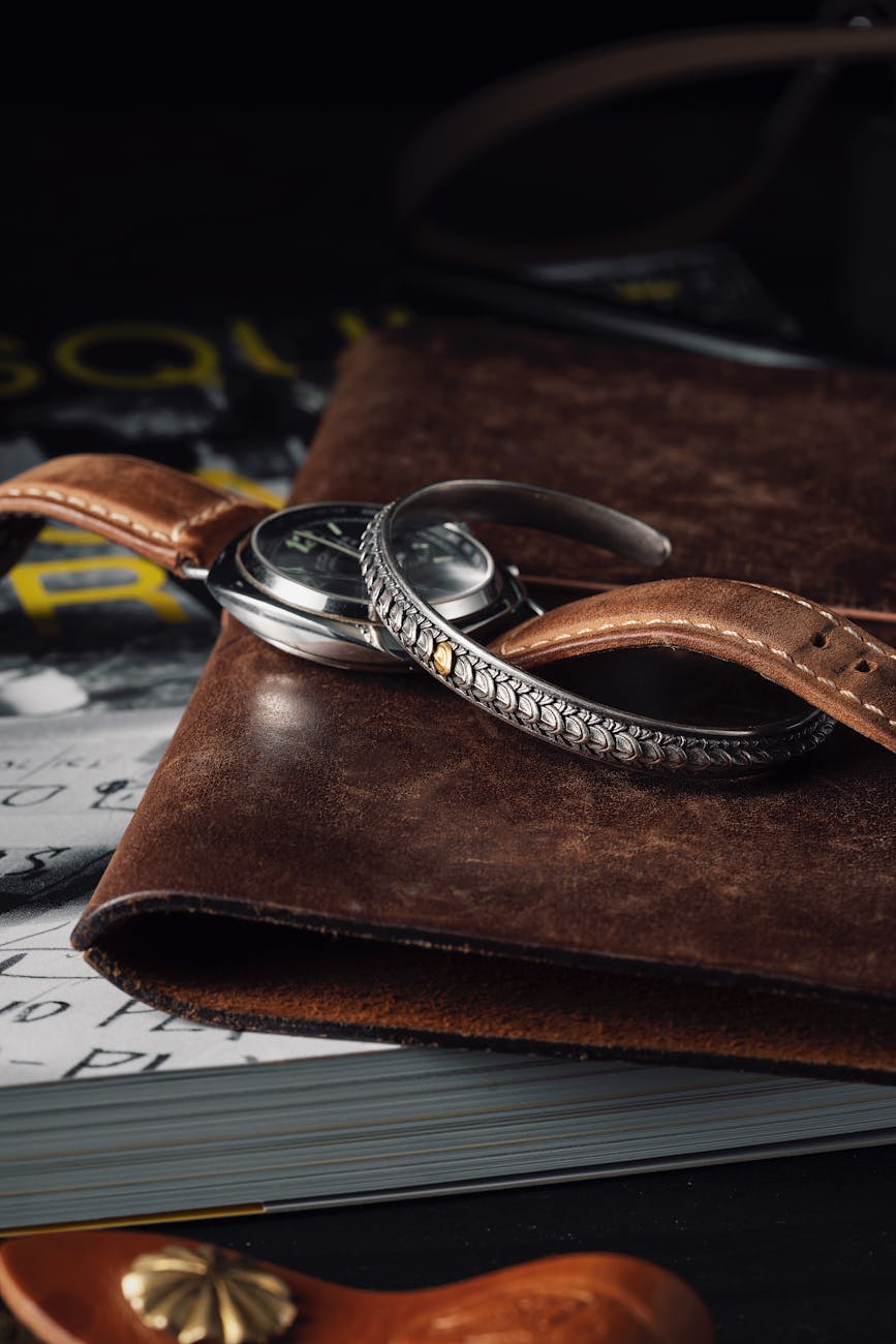 close up of a stylish wristwatch with leather and silver bracelets on a leather notebook