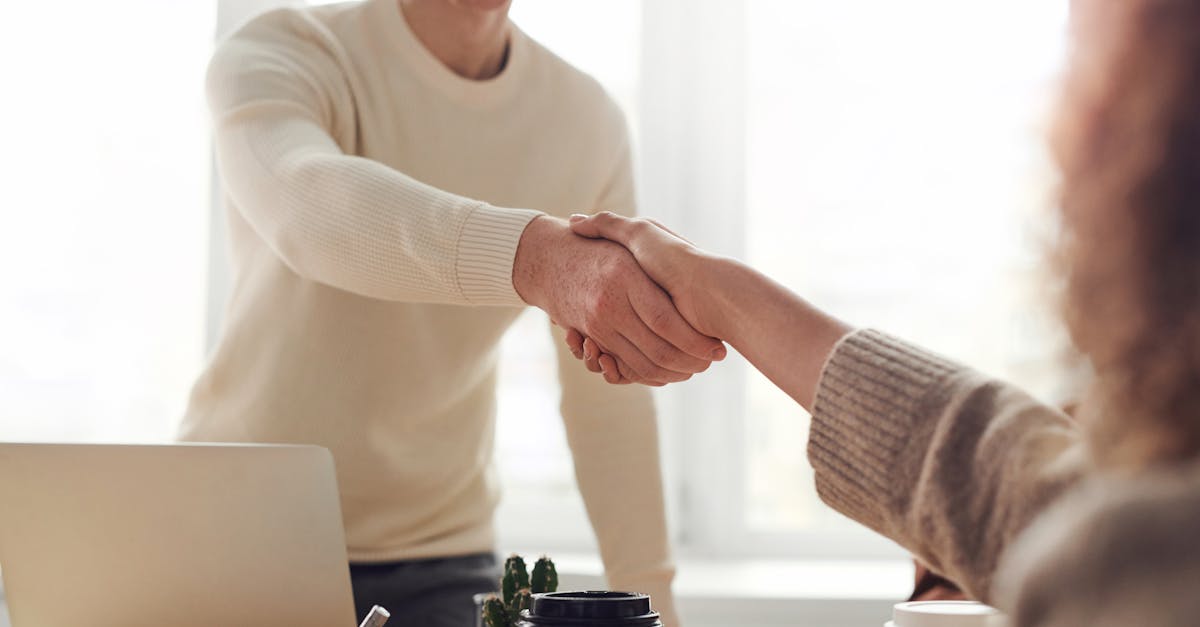 close up of professionals shaking hands over coffee in a modern office