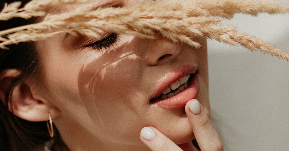 un portrait serein d une femme les yeux fermes touchant son menton avec de l herbe de ble caressant doucement son visage