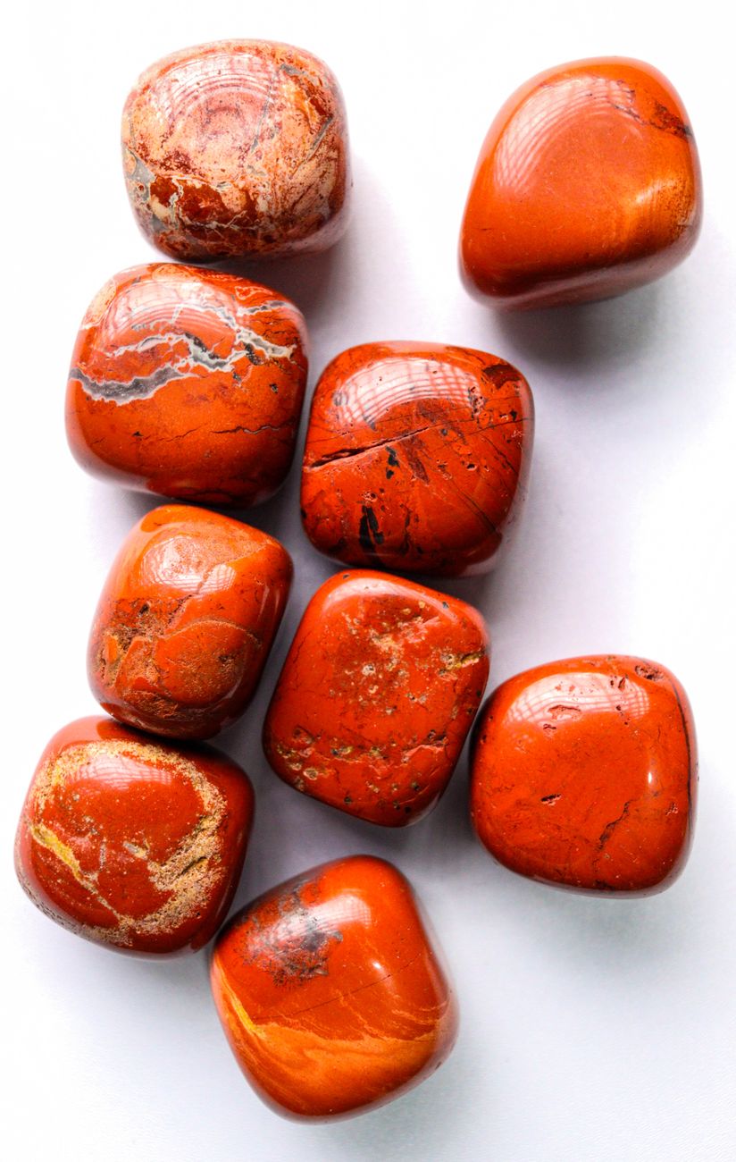 un ensemble de pierres de jaspe polies d un rouge orange eclatant sur fond blanc