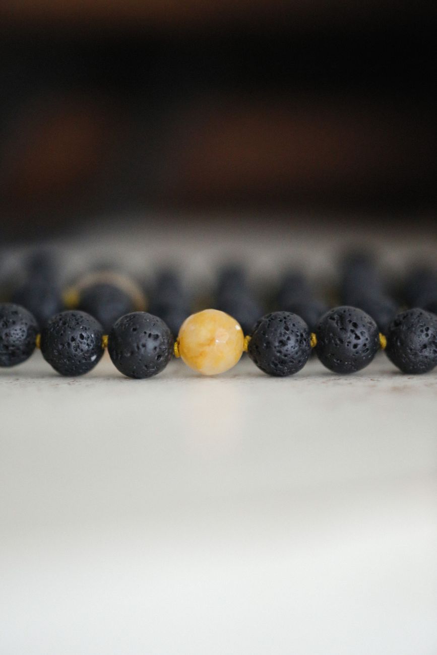 photo macro detaillee d un collier en perles noires avec une seule perle jaune pour le contraste