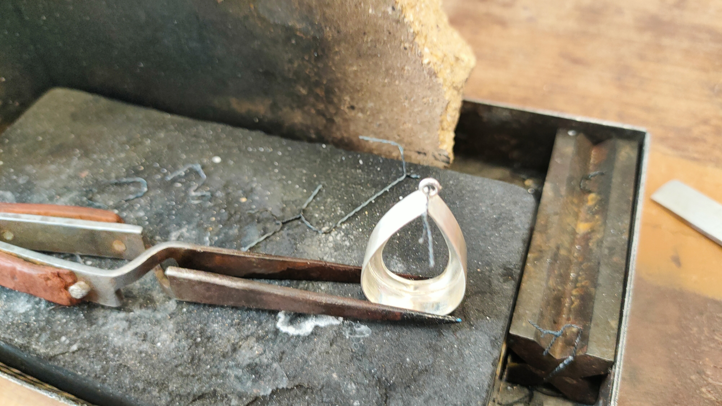 Artisanat joaillier : étape de soudure au chalumeau de la sertissure en argent pour un pendentif