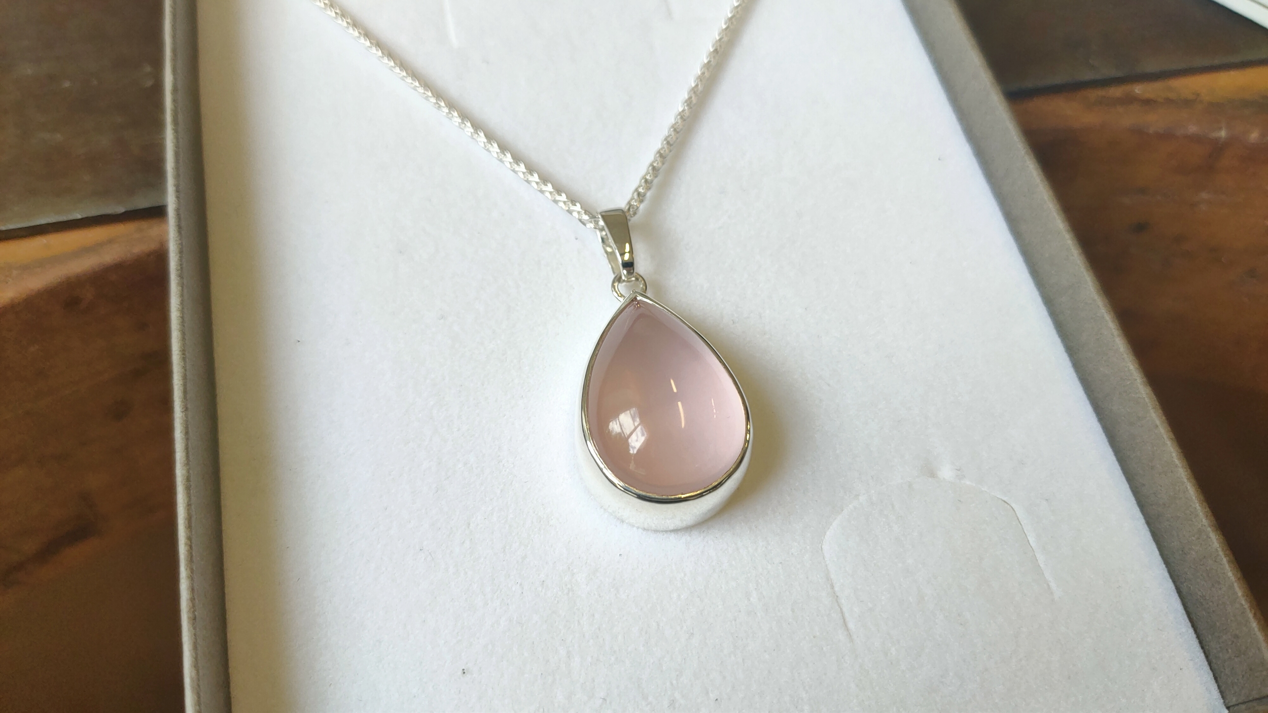 Détail du travail de finition et de polissage sur un pendentif en quartz rose sur mesure