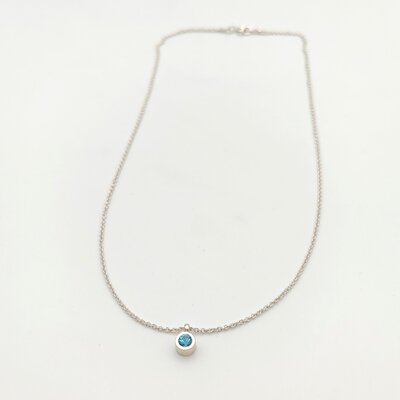 Photographie de produit professionnelle d'un collier pendentif en argent 925 avec topaze bleue ronde en serti clos sur fond blanc. Chaîne maille vénitienne de 41 cm. Élégance minimaliste