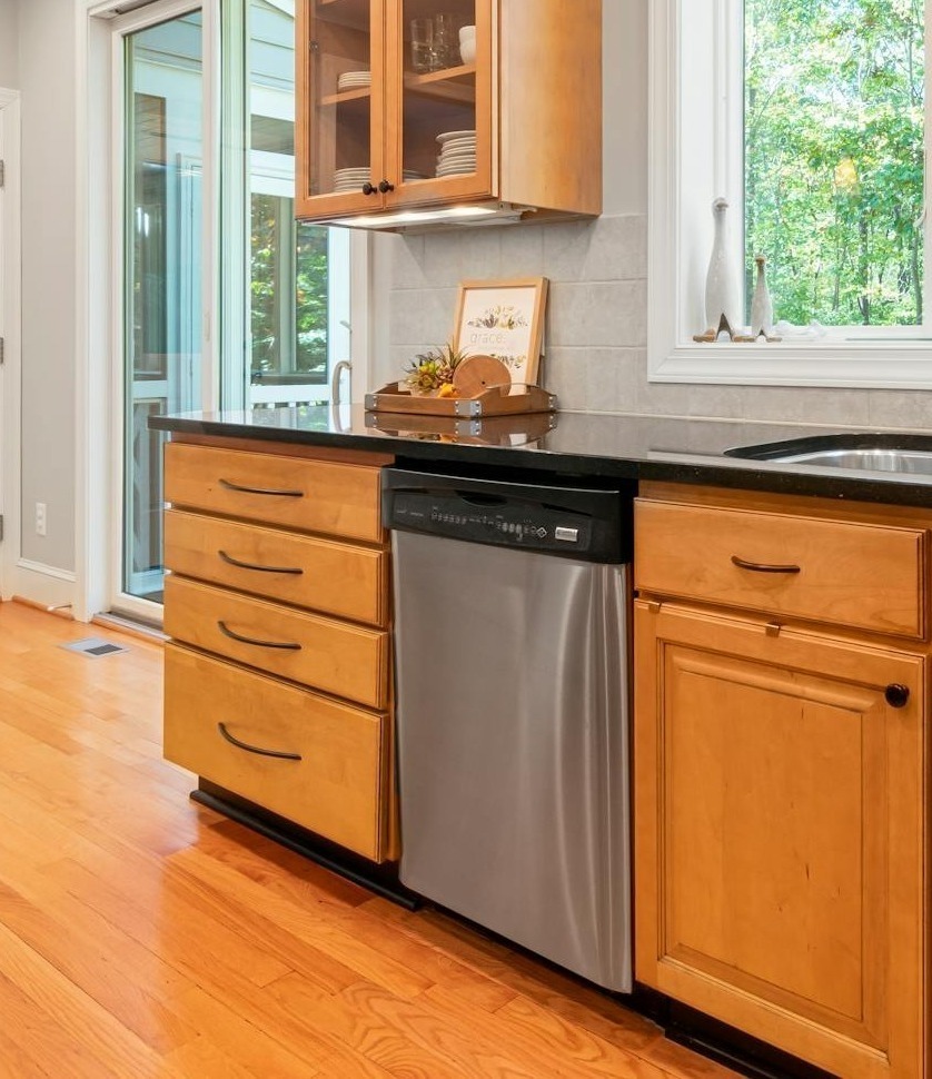 spacious kitchen featuring wooden cabinets large windows and a stainless steel dishwasher