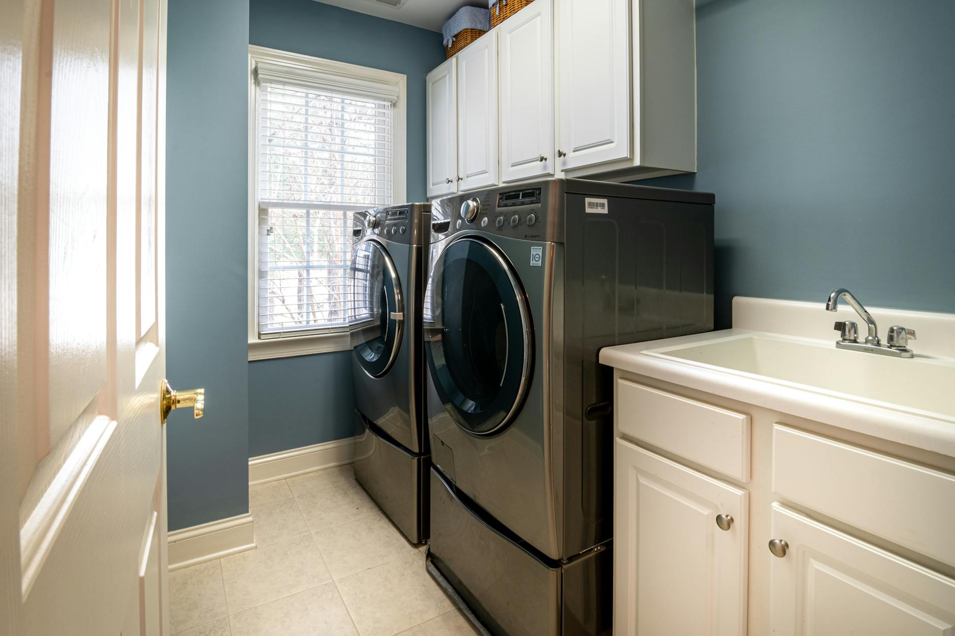 a clean organized laundry room featuring modern appliances and ample storage
