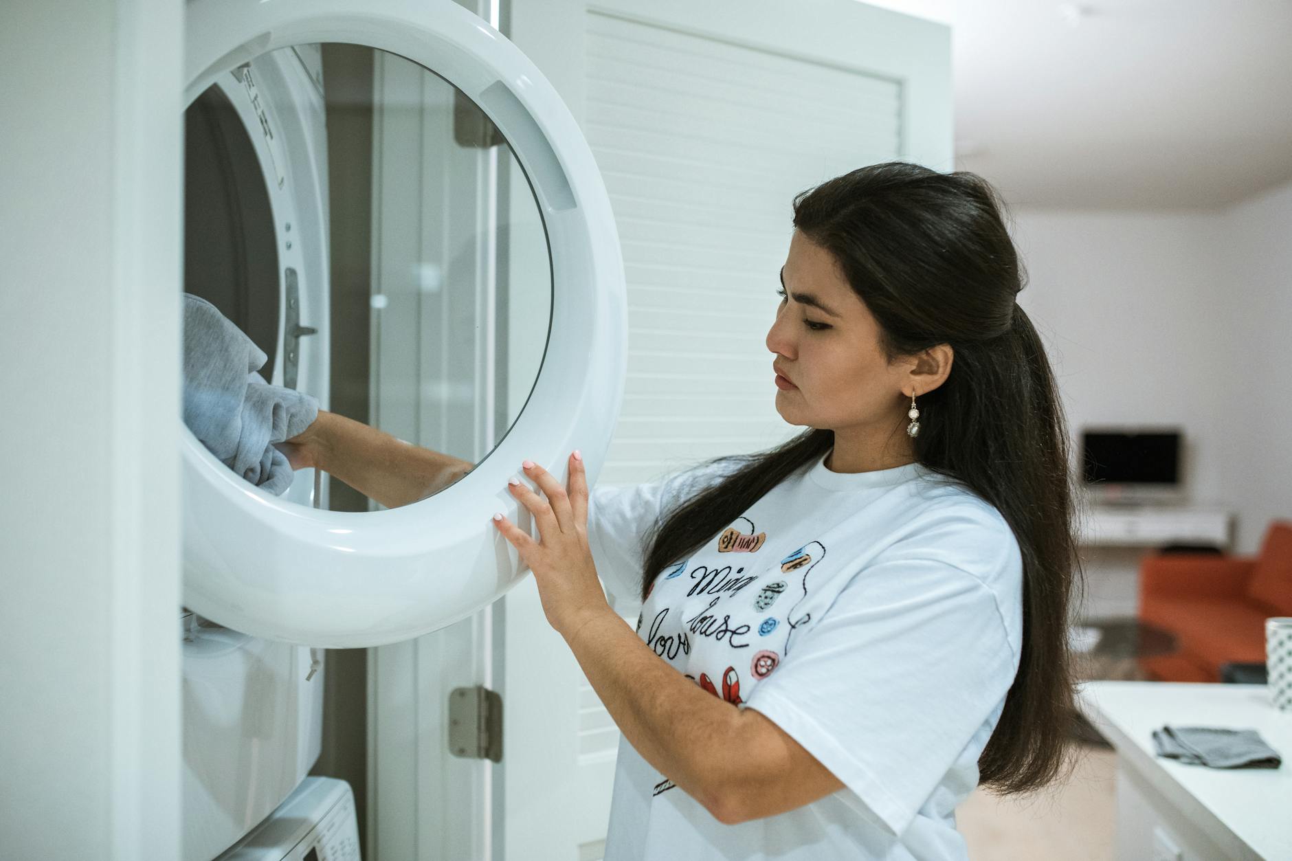 a woman loads clothes into a modern washing machine focusing on laundry in a stylish home setting