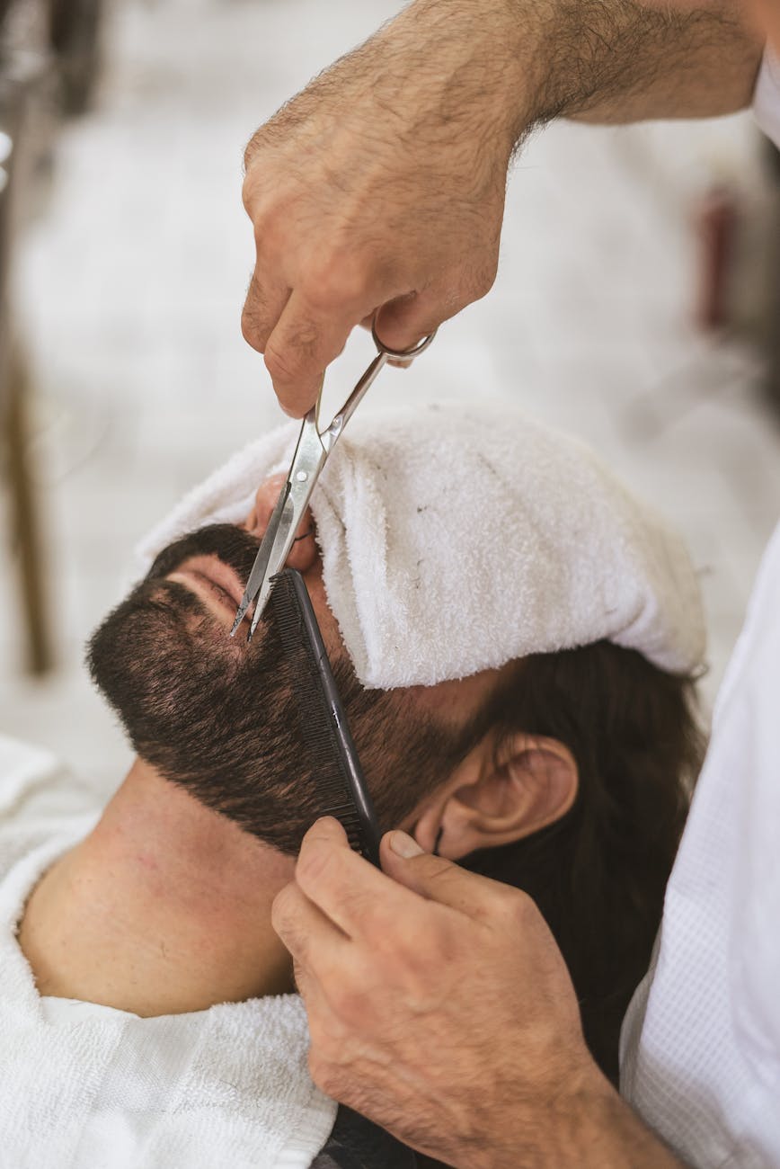 un coiffeur soigne les poils du visage d un client
