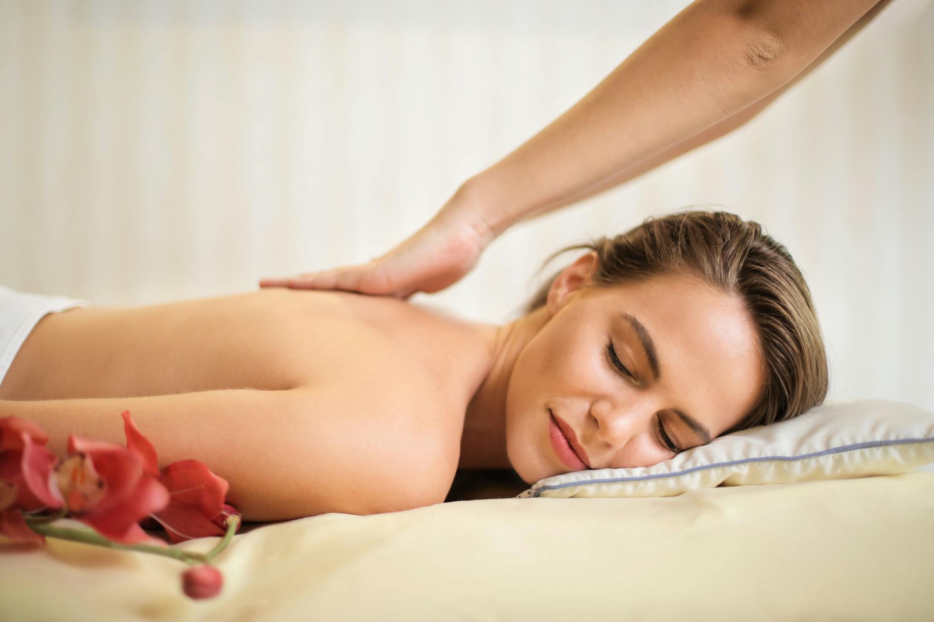 femme aux seins nus allongee sur le lit se faire masser